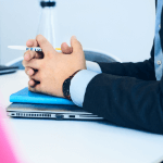 hands folded over a laptop