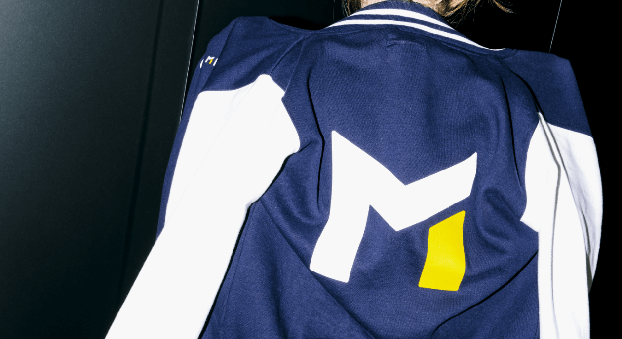 back view of a jacket with a bold M logo in white and yellow
