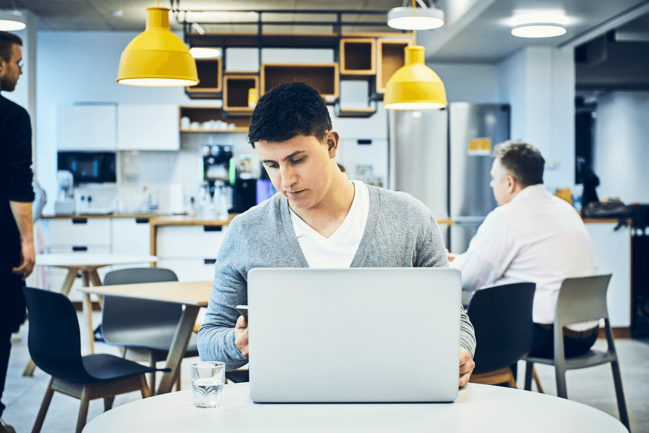 a man working on his laptop with a glass of water on his table next to him