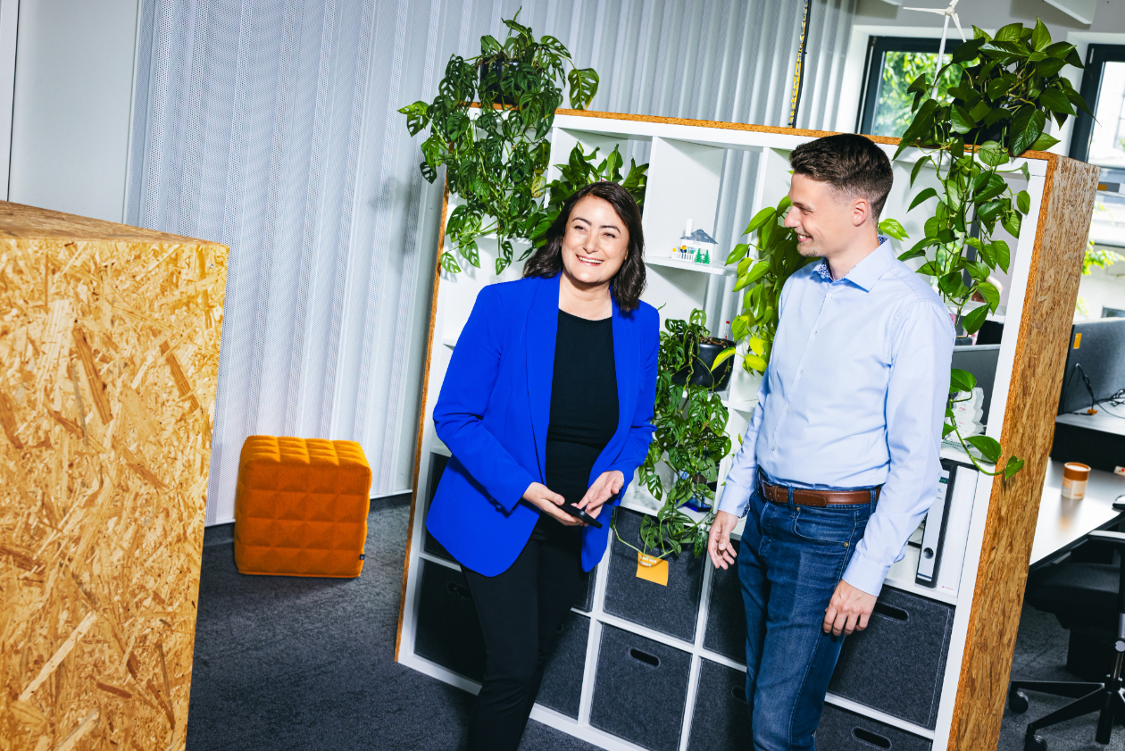 two professionals conversing in the middle of a modern and green office space