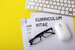 CV, curriculum vitae with computer keyboard on yellow background, top view