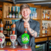 Smiling Bar Staff holding a pint behind the bar 