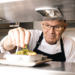 A Kitchen manager wearing an apron looking at a meal that is being served