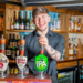 Smiling Bar Staff holding a pint behind the bar