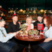 Five smiling Greene King workers sat around a table in Christmas fancy dress with presents on the table