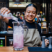A smiling bar staff at Greene King pouring a drink