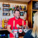 A smiling Greene King pub manager serving a pint of beer