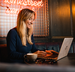 women smiling whilst looking at her laptop
