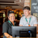 assistant manager at Greene King on the till with team member - both smiling