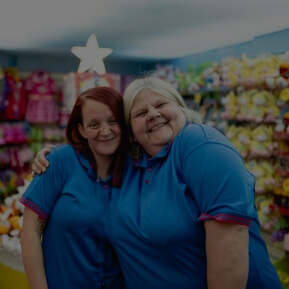 Image of two shop workers embracing and smiling