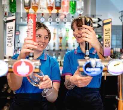 Image of teammates laughing as the pour drinks at the bar