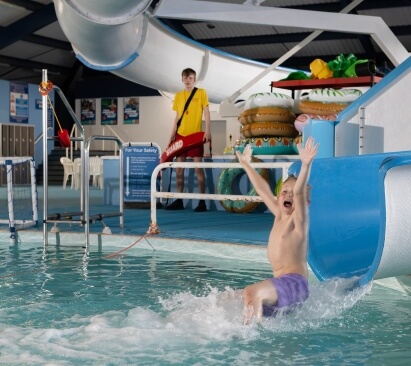 Image of child sliding down a waterslide into a pool