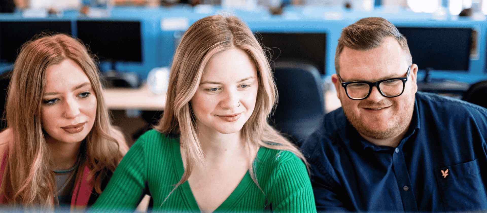 Image of three colleagues all smiling looking at the computer