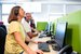 3 people sit at computers in an office, each has a headset on.