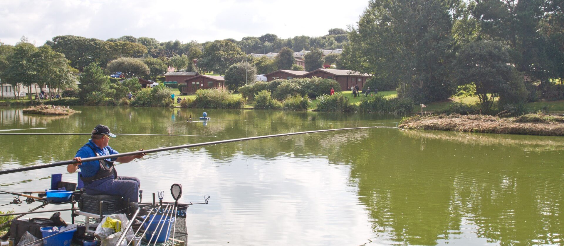 Image of a man with a fishing rod by the edge of a lake