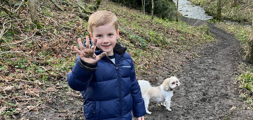 Image of a little boy and dog walking in the woods