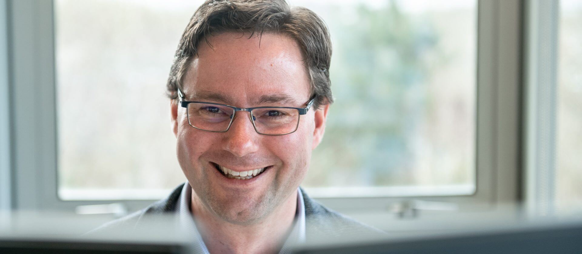 Image of a man smiling at a computer screen