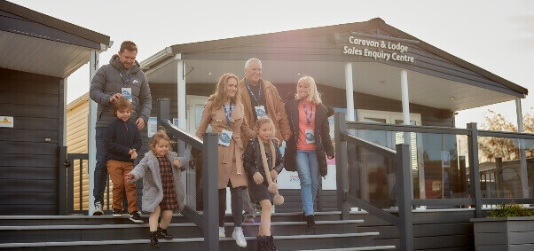 An image of a large family walking down a set of steps out the front of a caravan and lodge sales enquiry centre