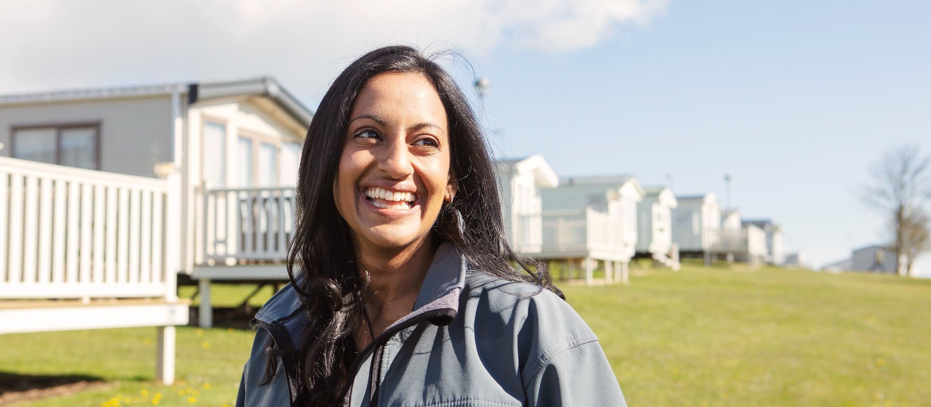 Image of manager smiling stood in front of a line of mobile holiday homes