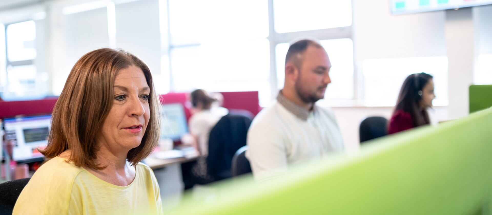 Image of a man and a woman working at their desks looking at their computer screens