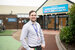 A man in a smart shirt with a purple lanyard on standing on a pathway.