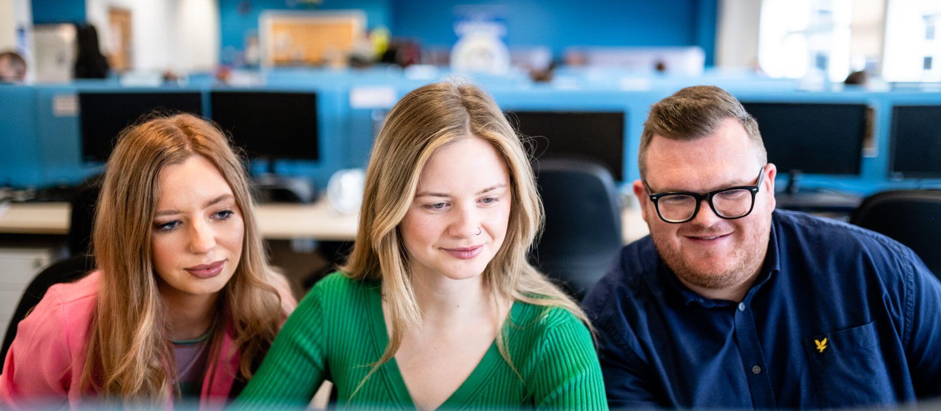 Image of three colleagues looking at their computer screen