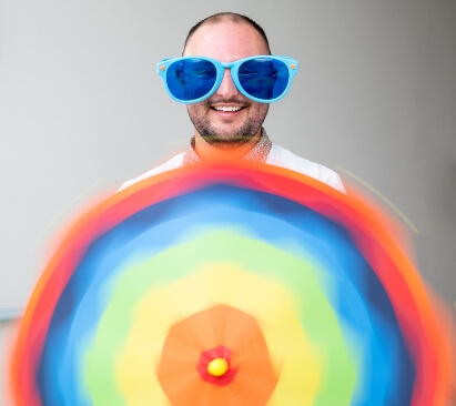 image of a man with a rainbow parasol and blue oversized sunglasses