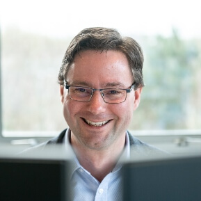 a man smiling looking at his computer monitors
