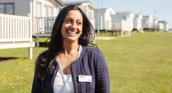 A woman smile and looks to her left with caravans in the background