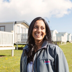 A woman smile looking to her left with holiday homes in the background