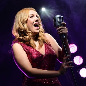 Image of woman in red sequin dress singing on stage