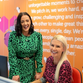 image of two women sat behind a desk laughing