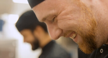 Image of chef looking down and laughing while working