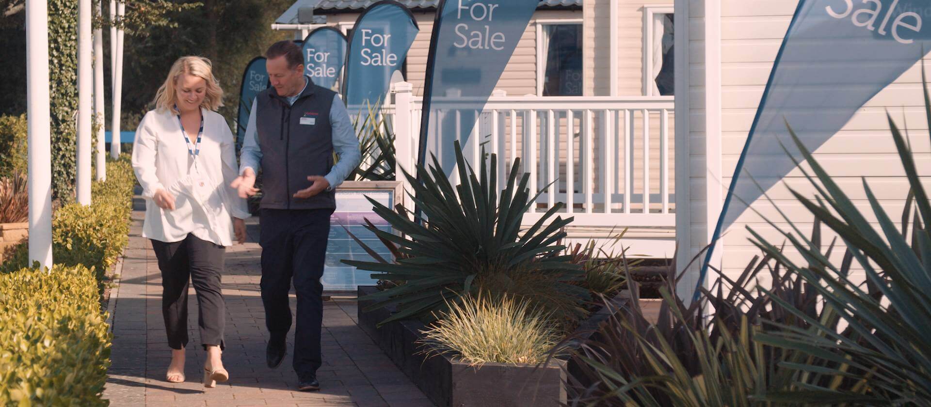 Image of man and woman walking past for sale signs mid discussion