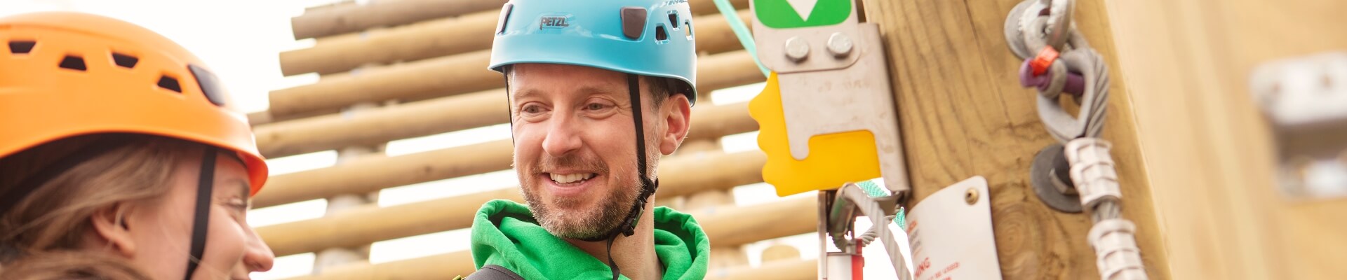 Image of two work colleagues in hard hats smiling while on a high ropes course