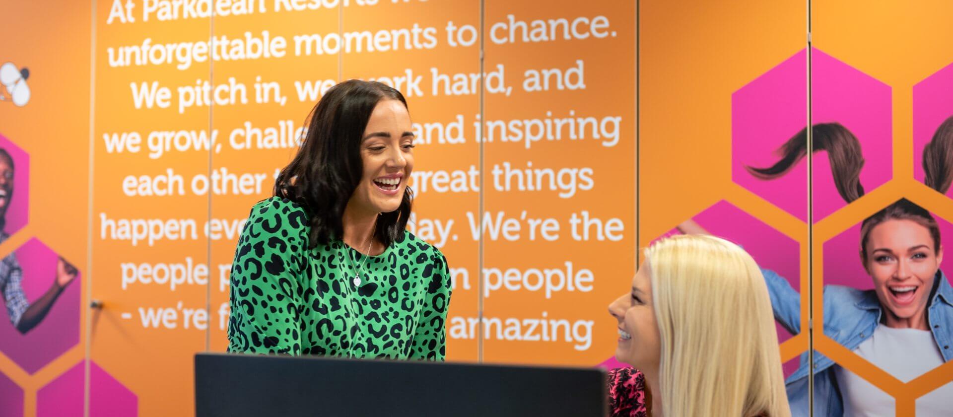 An image of two women laughing at their desk