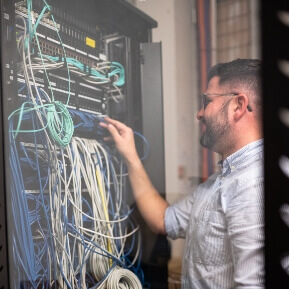 a man working working with computer wires class=