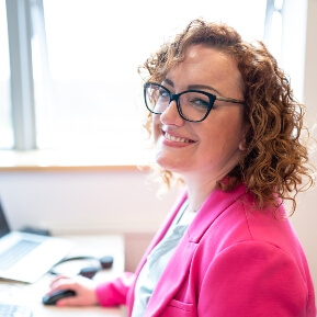 image of a woman moving a computer mouse, smiling at the camera