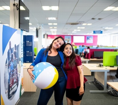 Image of 2 colleagues smiling with their arms around each other