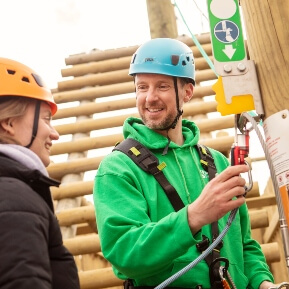 image of man wearing a helmet, dressed in safety gear, holding onto a harness