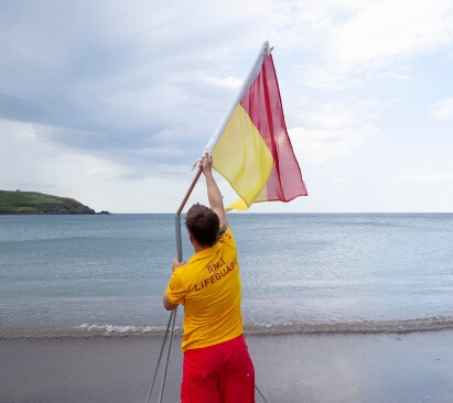 Lifeguard putting the flag up on the beach