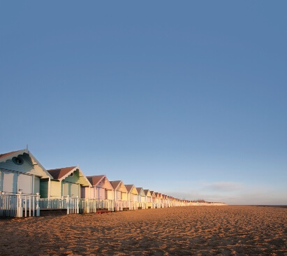 Image of colourful beach huts on a sandy beach