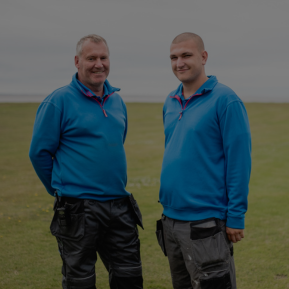 Image of two maintenance workers standing on a pitch