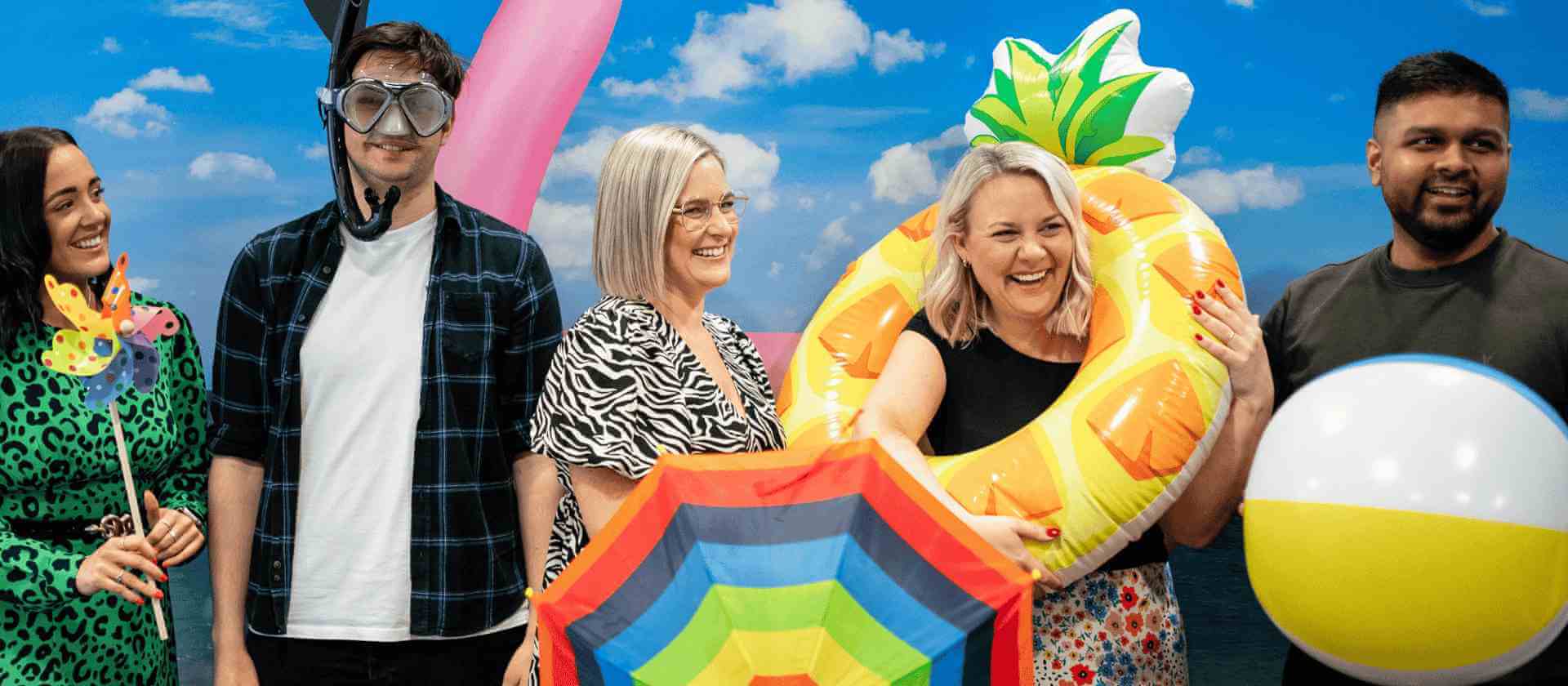 Image of a group of people smiling with beach props