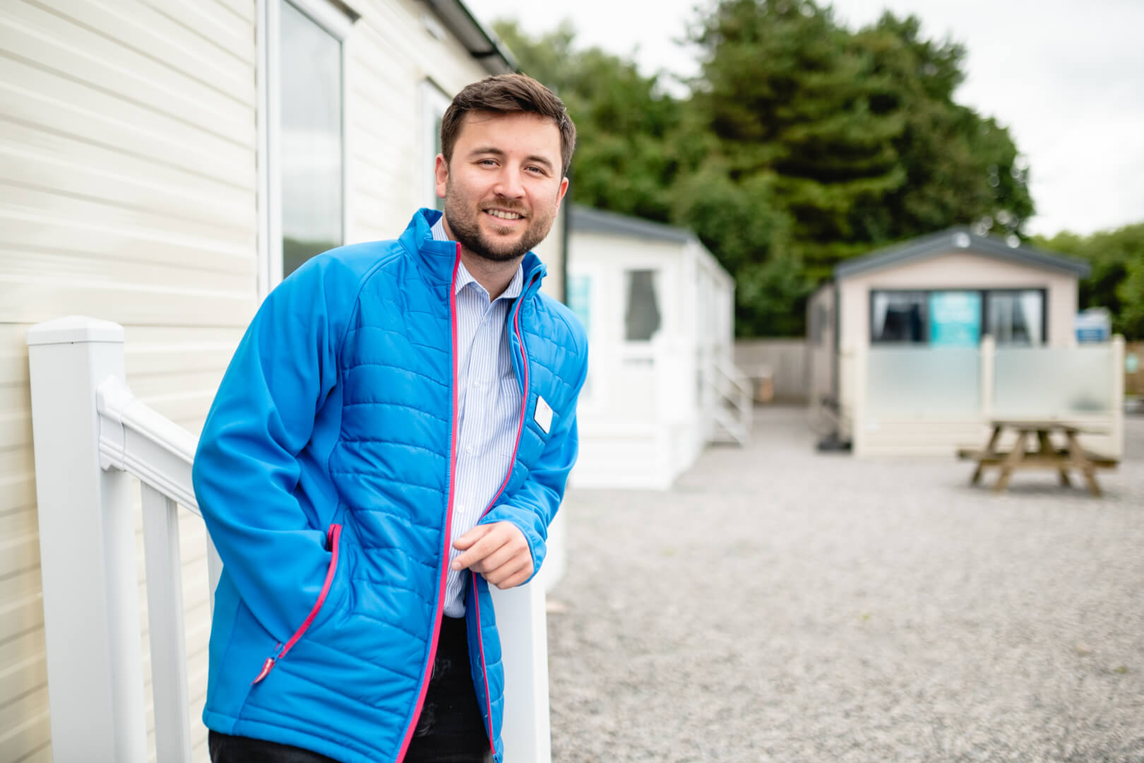 Image of a man in a navy suit smiling with his arm resting on top of a counter top