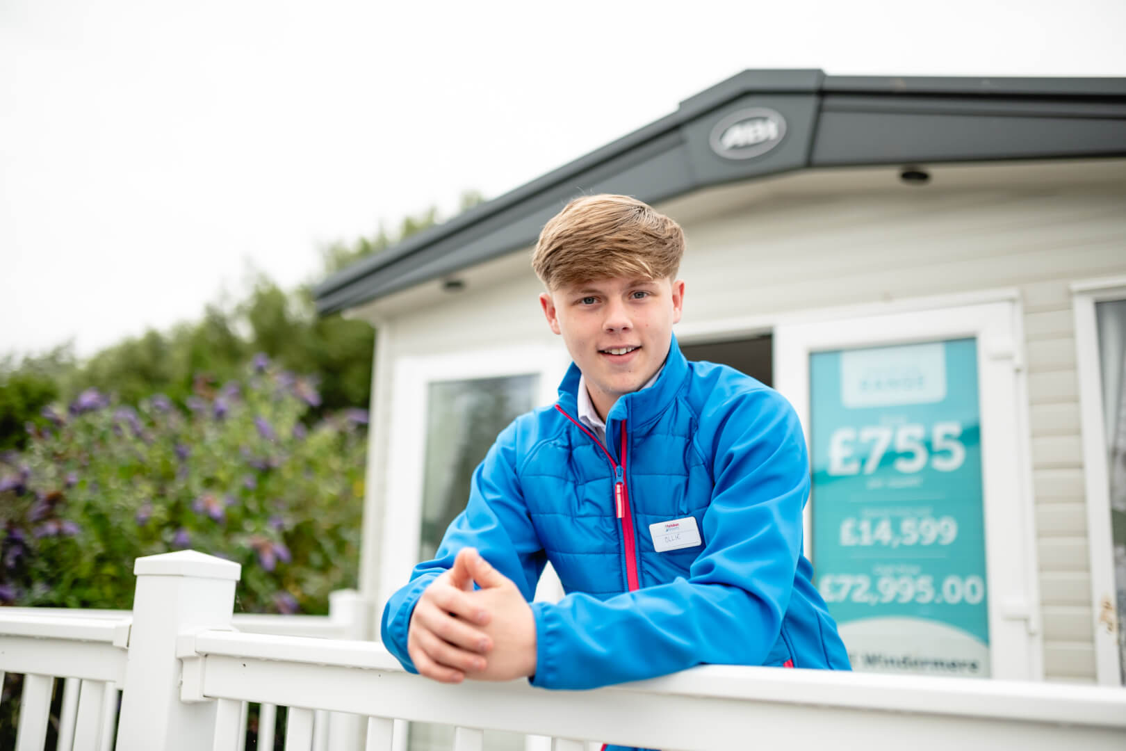 An image of three adults having a conversation in front of a holiday home and for sale sign.
