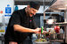 man in a commerical kitchen assembling a dish