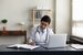 Clinical Manager at DBH sitting at desk with laptop, writing in notebook