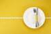 Measuring tape on a fork and knife - dieting concept image