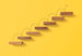Wooden blocks arranged in a shape of staircase on yellow background